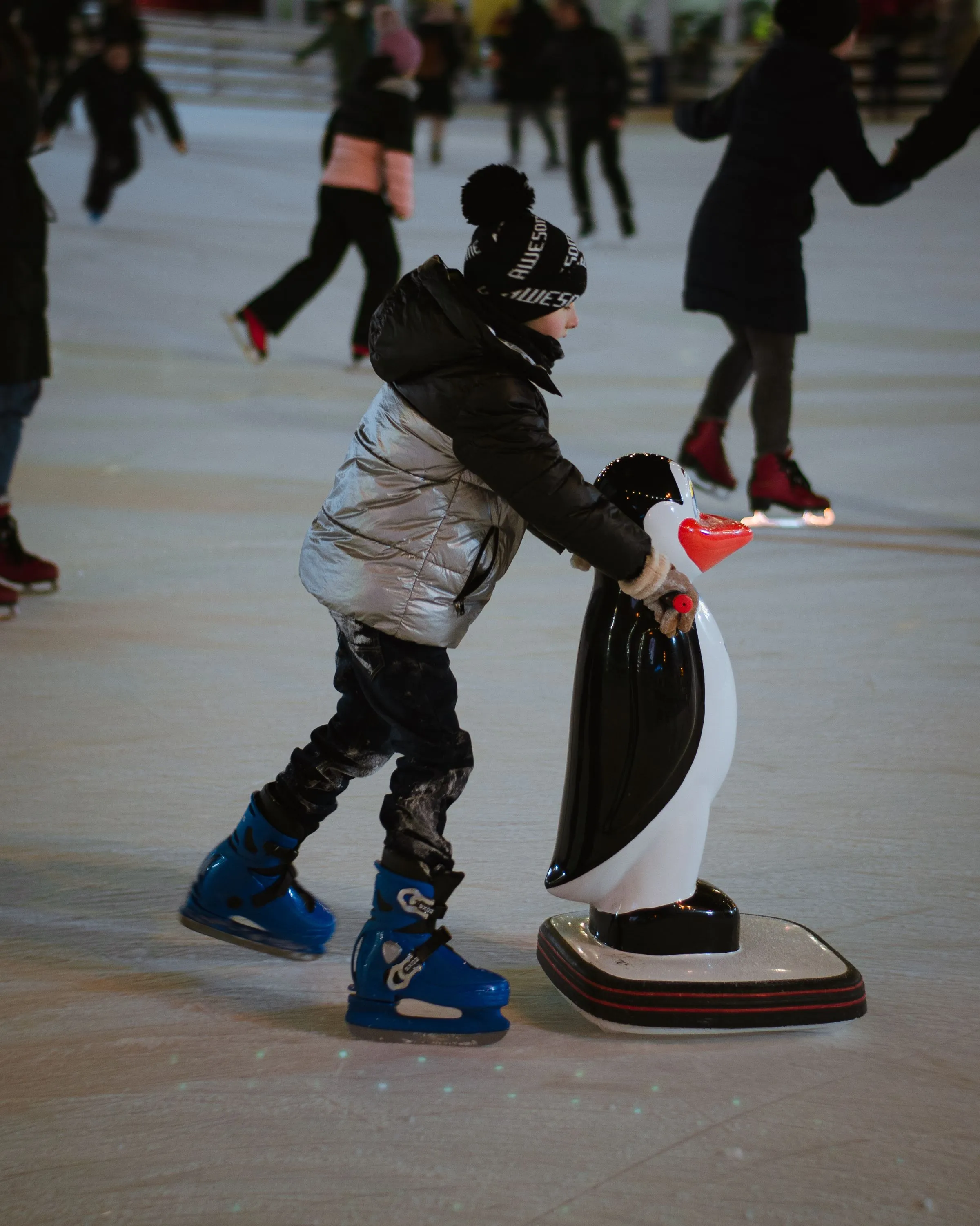 Kind mit Pinguin-Laufhilfe auf der Bahn